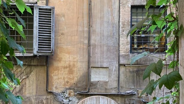 An old building with a central arched entrance, two windows with metal bars, and a door. - Residenza Domizia- Guest House (Rome)