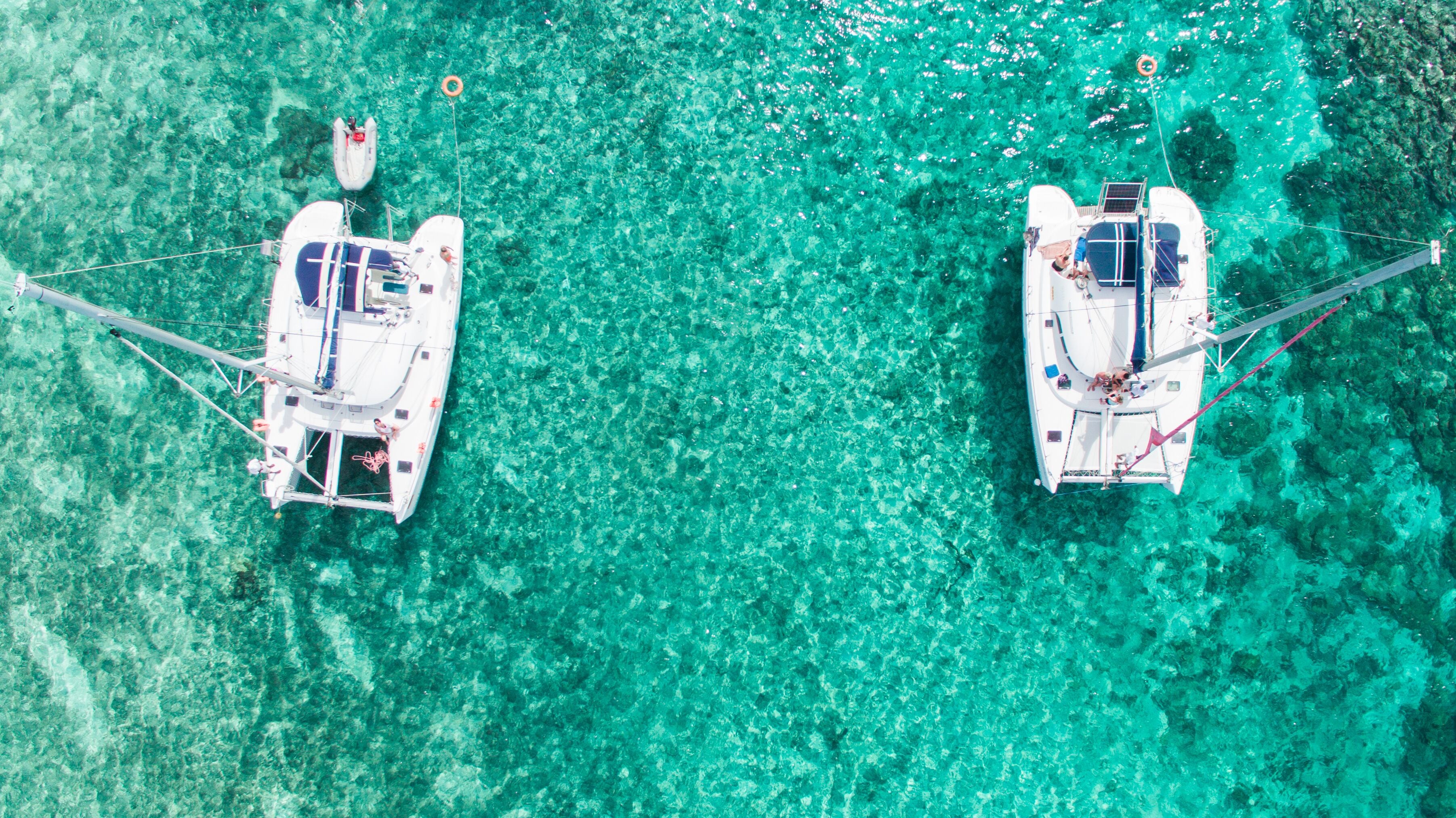 Two boats anchored in clear turquoise waters.