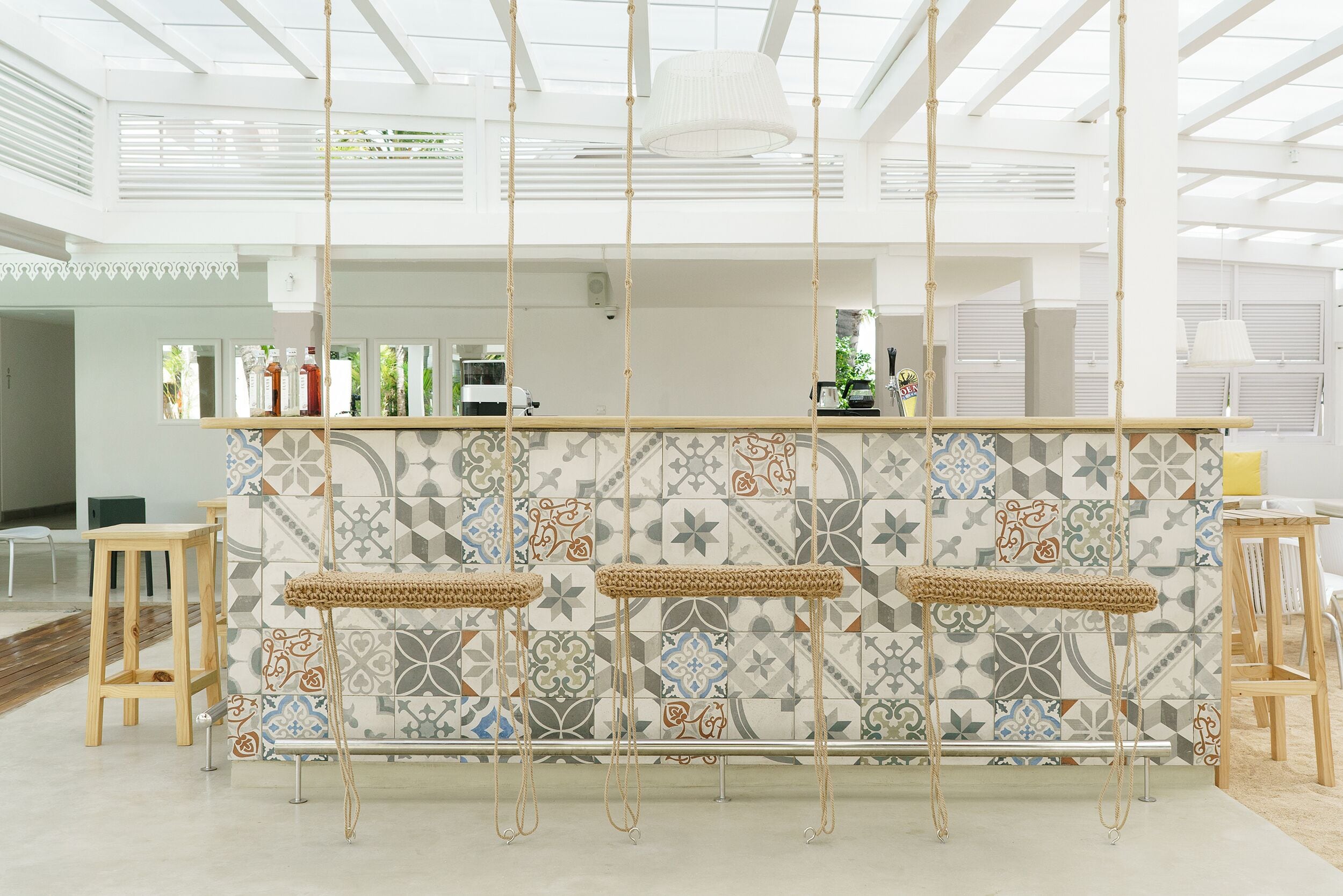 A reception area with a patterned tile wall, a wooden reception desk, and a hanging light fixture.