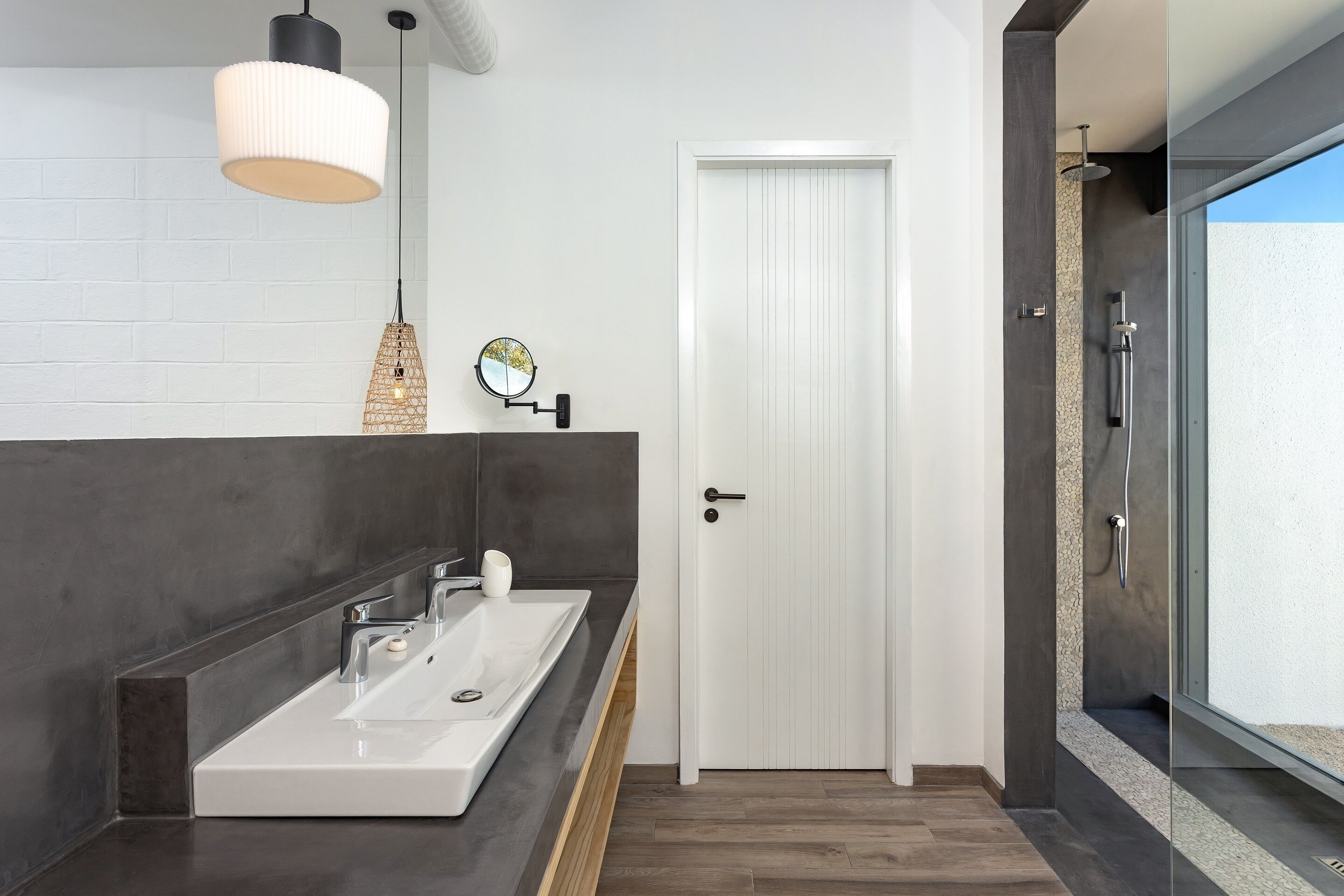 A modern bathroom with a large white sink, a mirror, and a hanging light fixture.