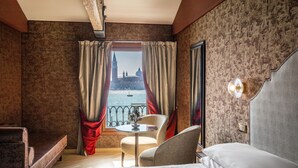 A hotel room with a bed, a small table, two chairs, and a view of a historic building through the window. - Hotel Paganelli (Venice)