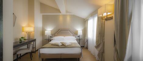 A modern hotel room with a large bed, bedside tables with lamps, a desk, and a chair.