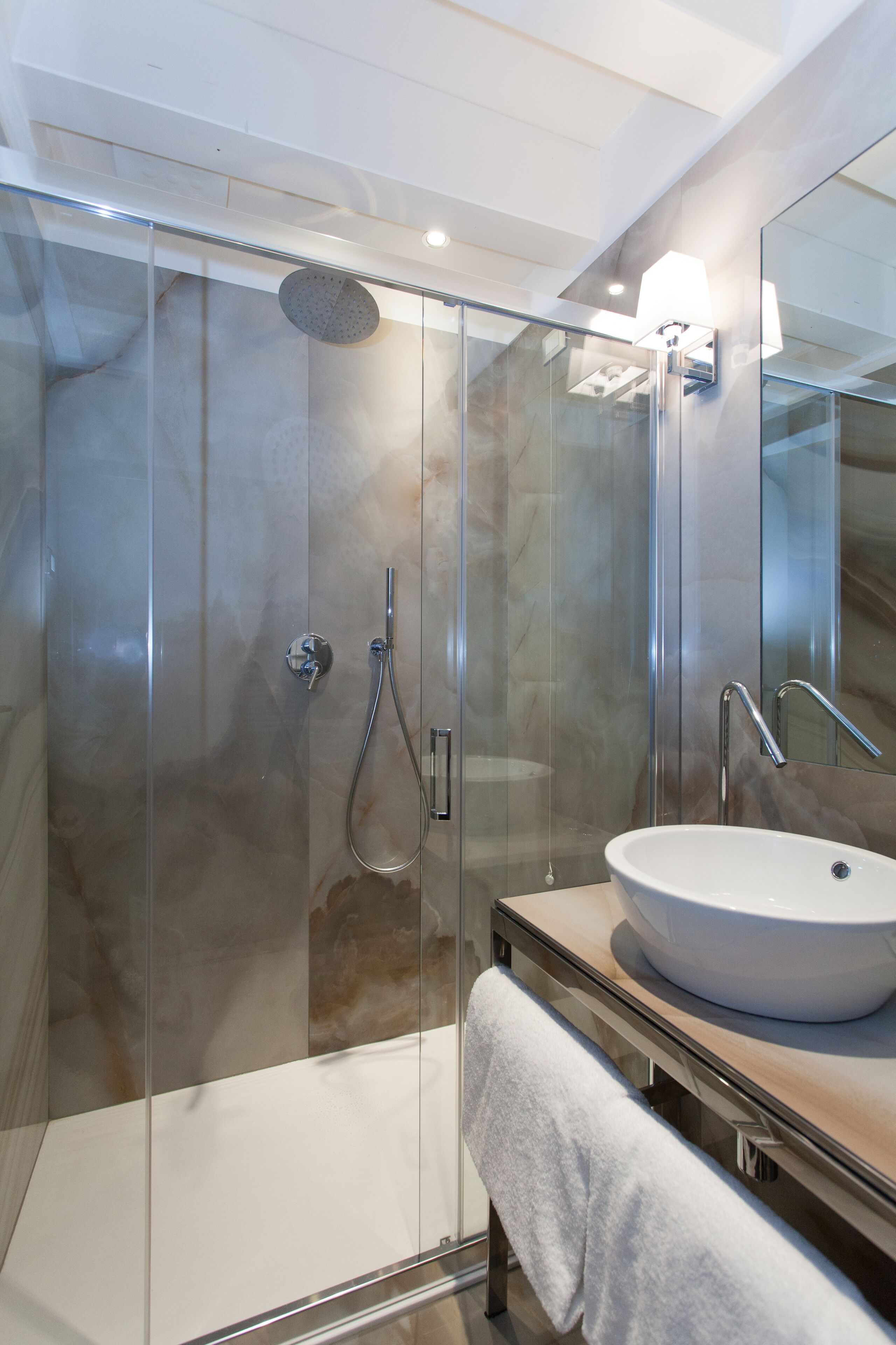 A modern bathroom with a glass-enclosed shower, a white sink, and a mirror.