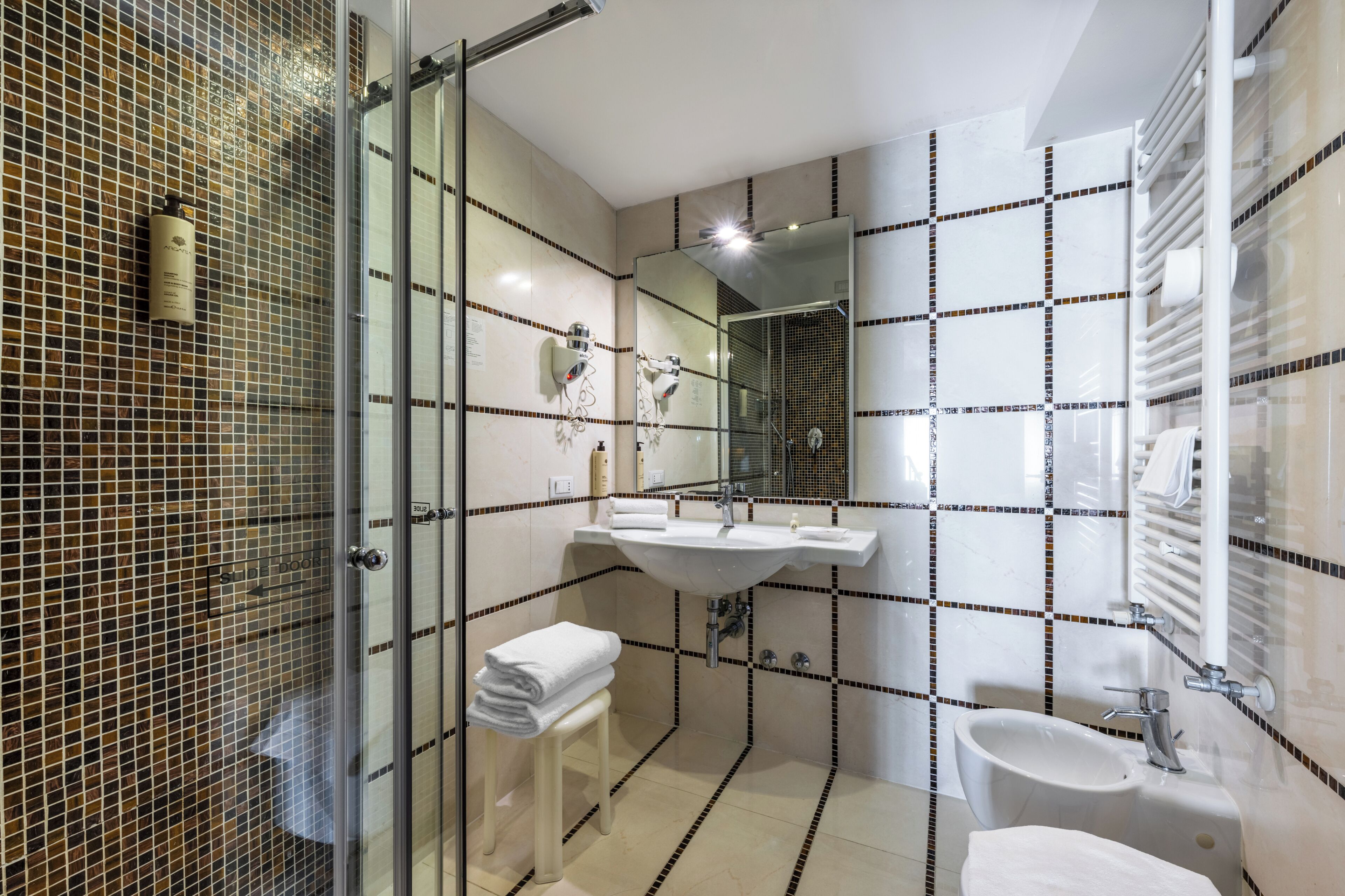 A modern bathroom with a glass shower enclosure, a vanity with a sink, and a separate pedestal sink.