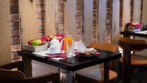 A breakfast table with fruits, a glass of orange juice, and a pitcher of water. - Hotel Paganelli (Venice)