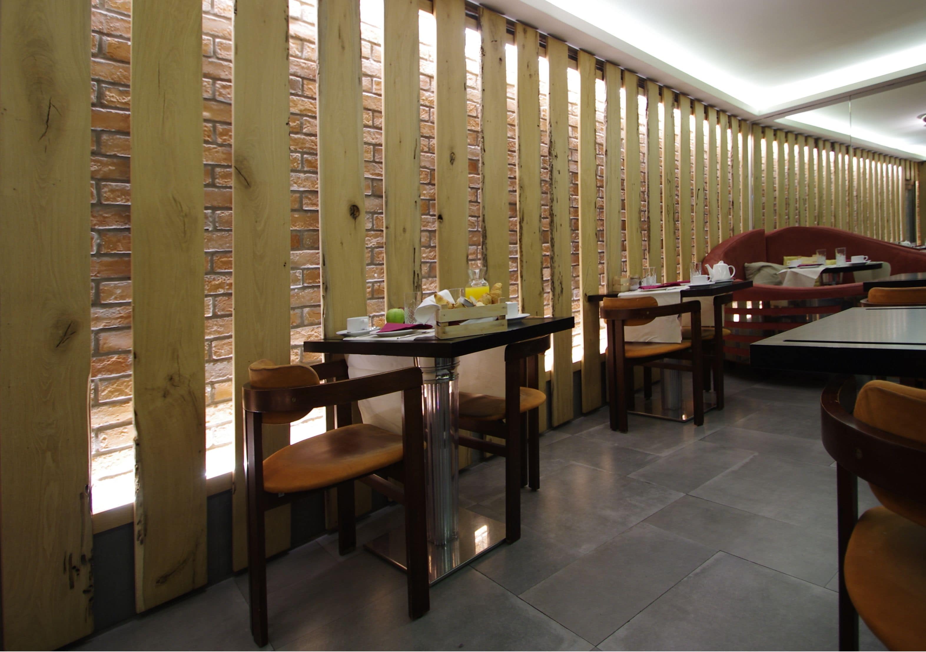 A restaurant with brick walls, wooden partitions, and several tables and chairs.