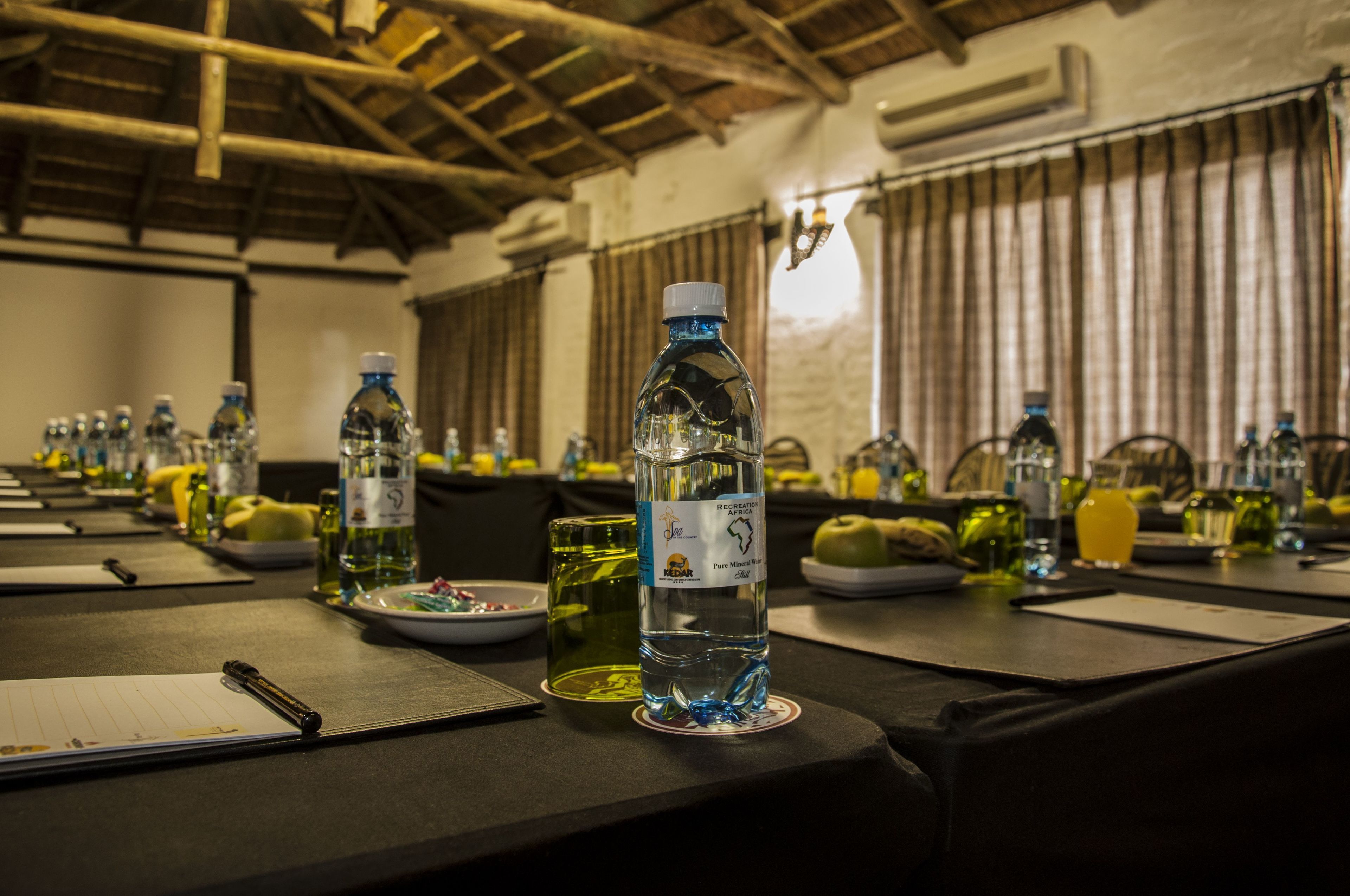 A conference room with tables set for a meeting, equipped with water bottles, glasses, and plates.