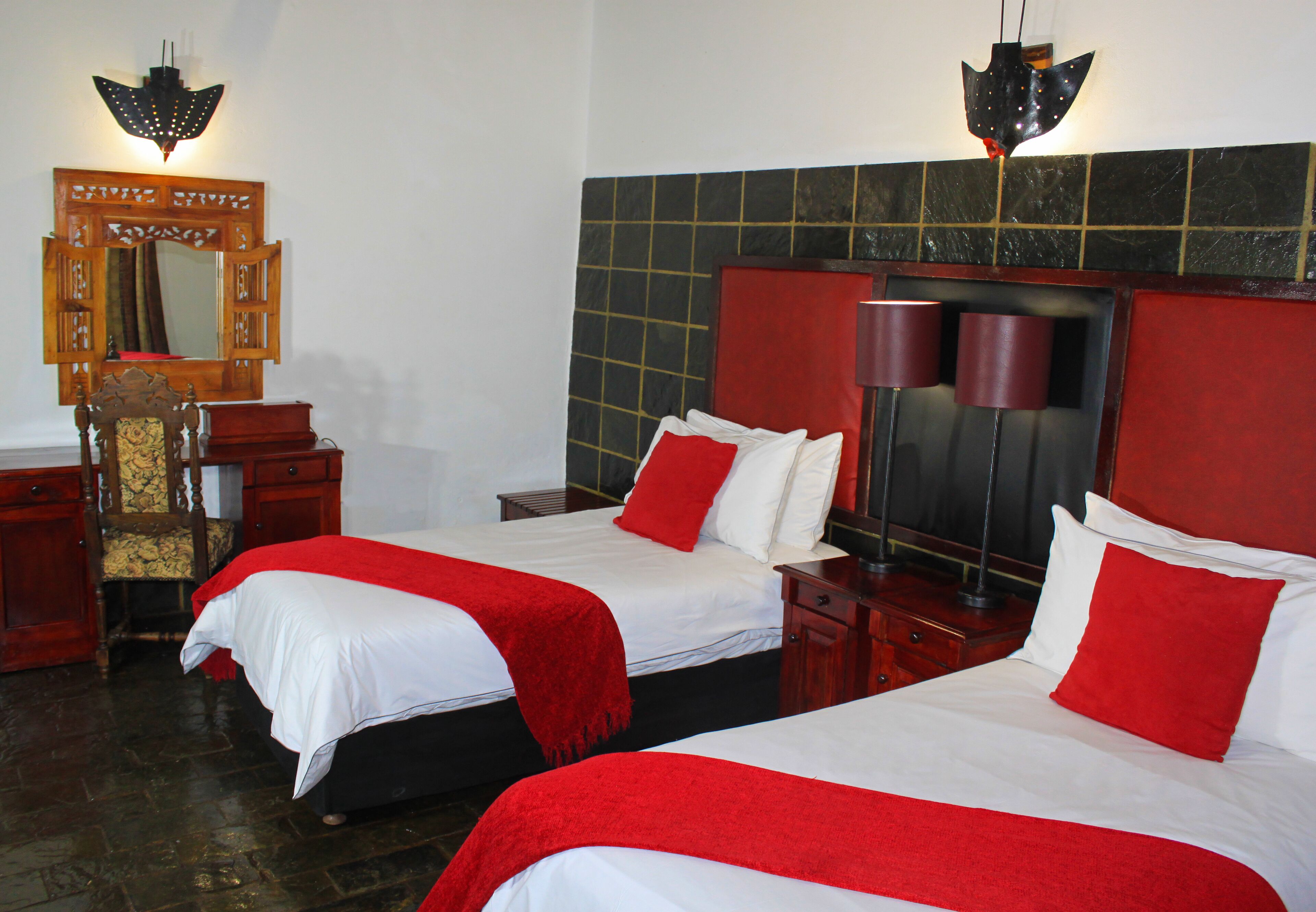 Una habitación de hotel con dos camas, un aparador de madera, un espejo y una pared de azulejos.