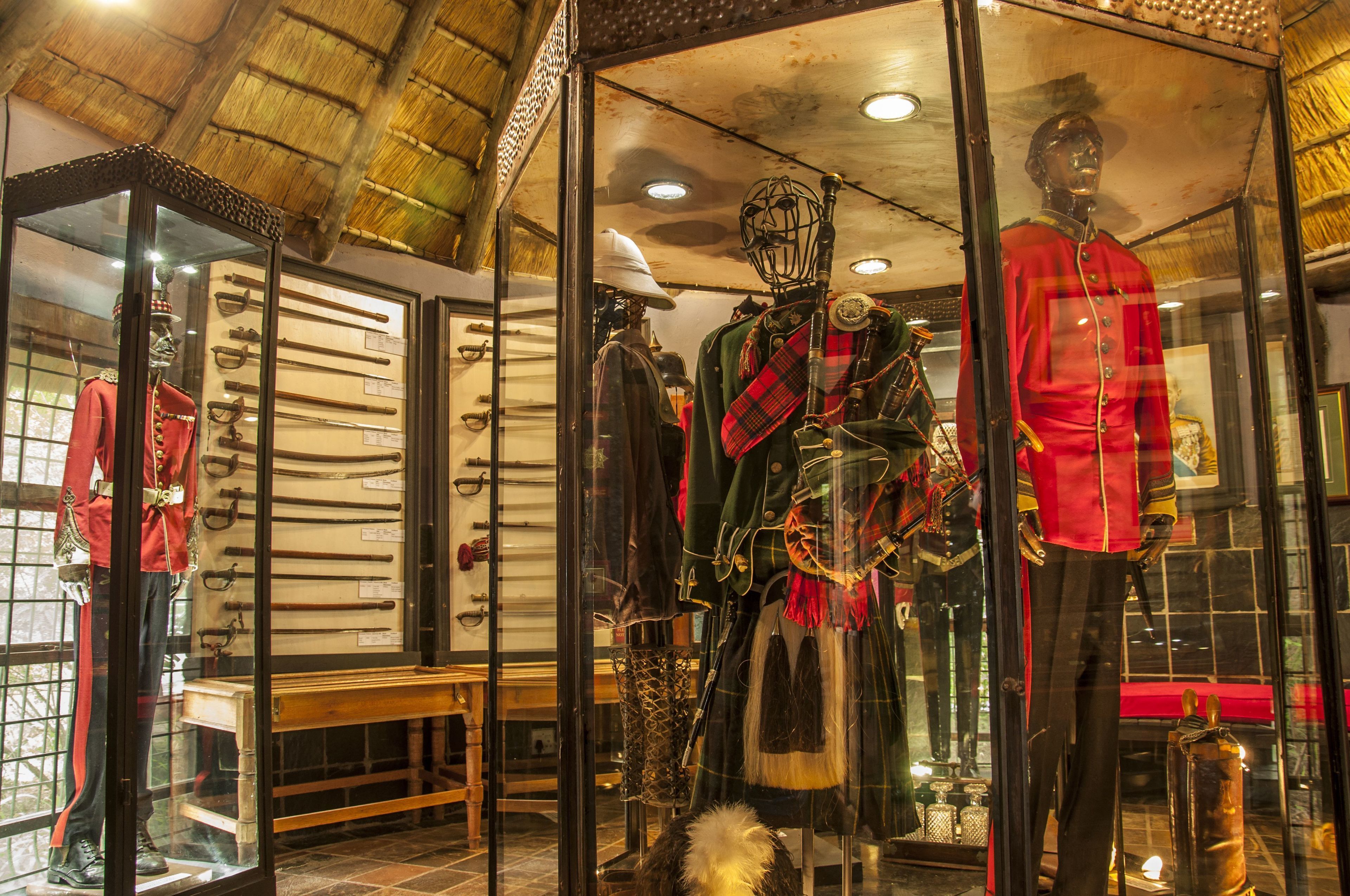 Mannequins in historische militaire uniformen, een zwaardenuitstelling en een rustiek plafond.