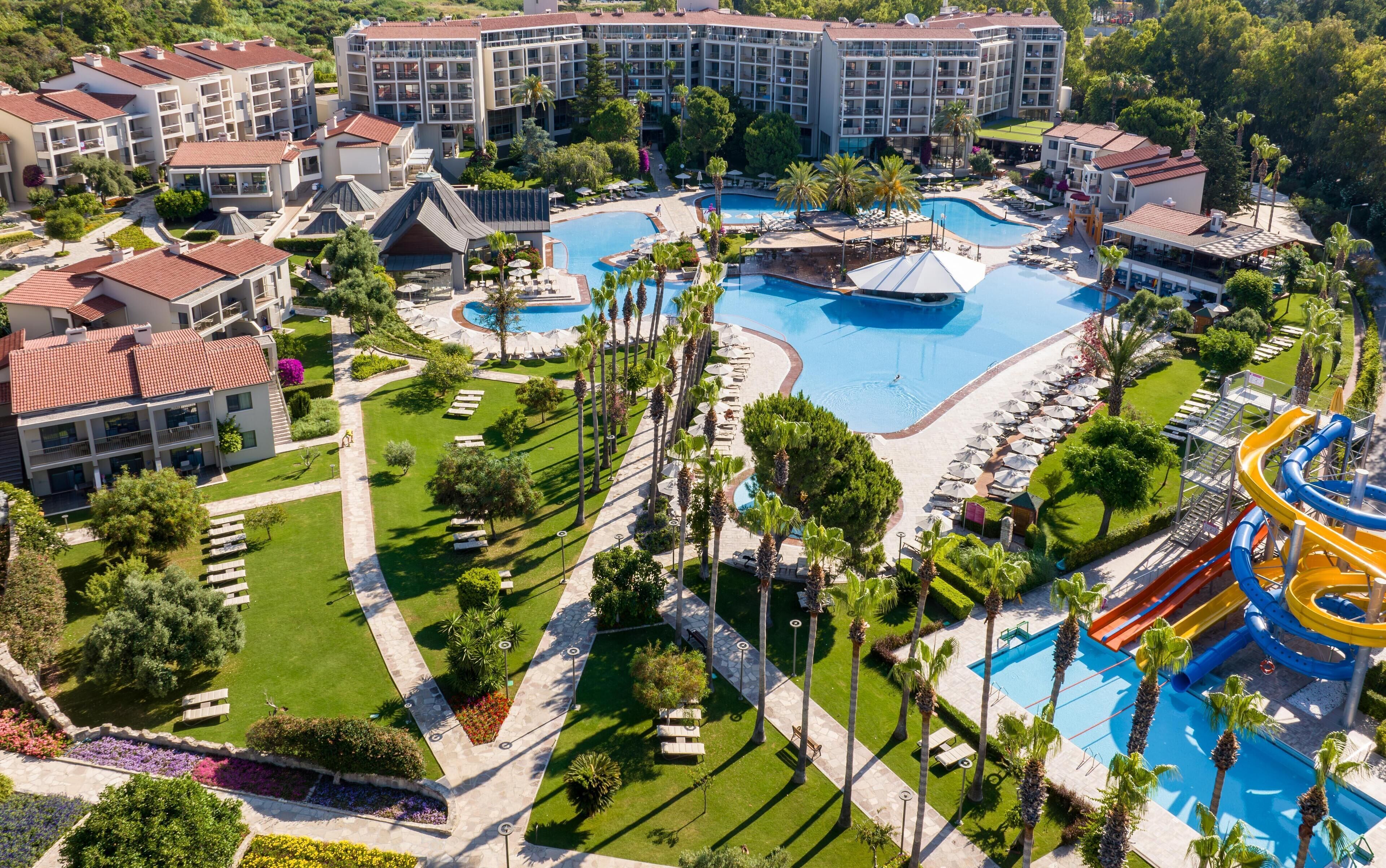 Un resort con múltiples piscinas, palmeras y un tobogán de agua.