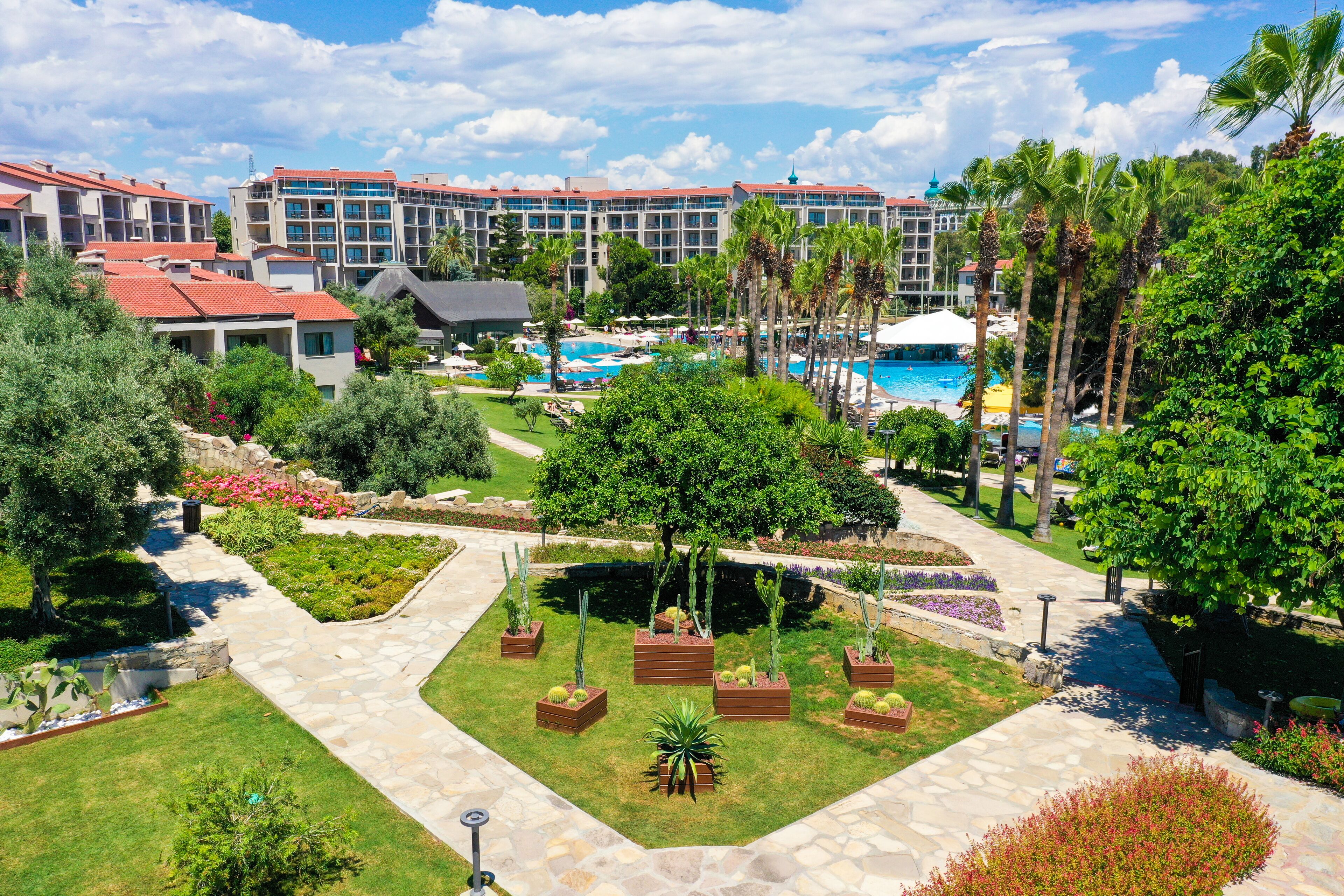 Un resort con piscina, palmeras y un jardín bien cuidado.