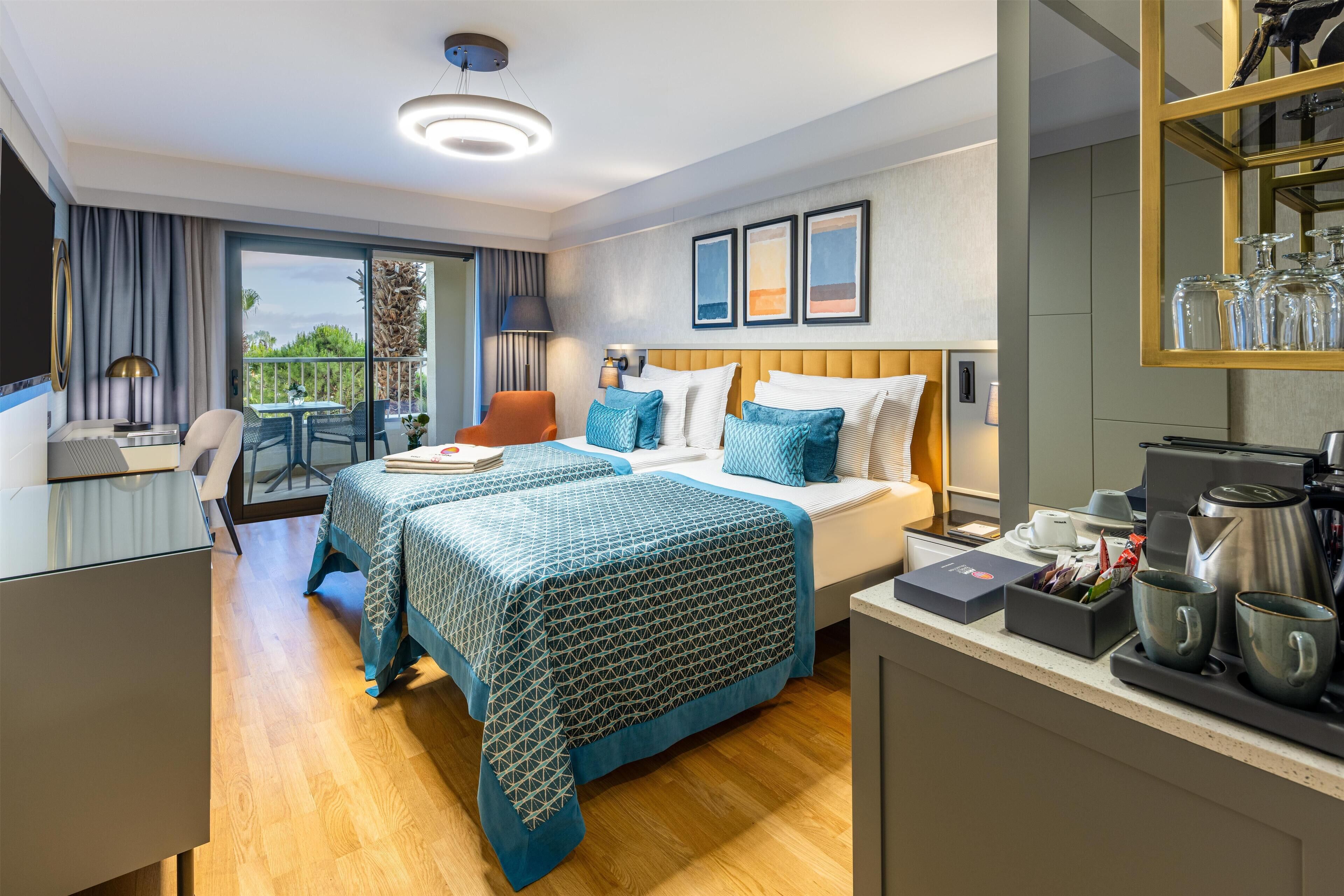 Une chambre d’hôtel moderne dotée d’un grand lit, d’un bureau, d’une chaise et d’un balcon offrant une vue sur la mer.