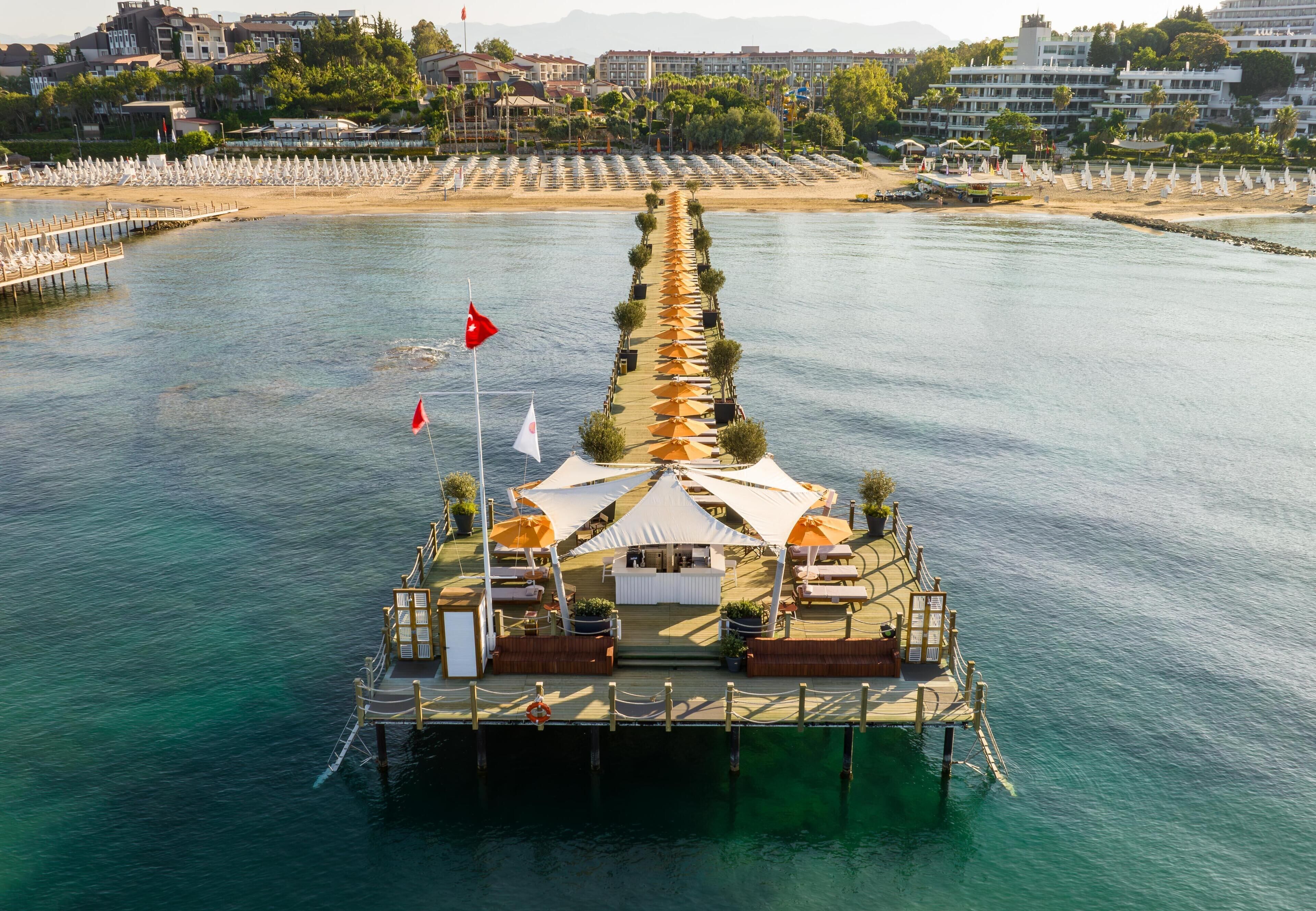 An aerial view of a floating restaurant with a deck, umbrellas, and seating areas.