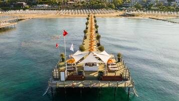 An aerial view of a floating restaurant with a deck, umbrellas, and seating areas.