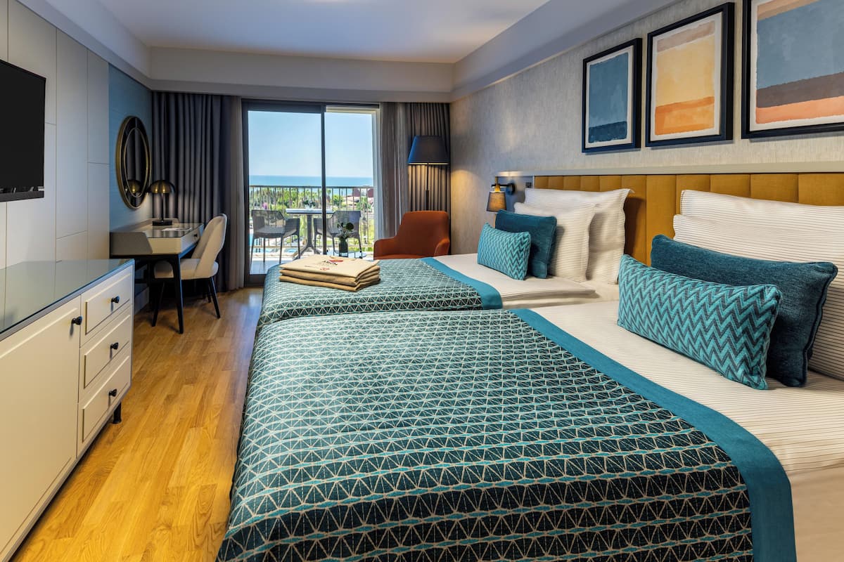 Une chambre d’hôtel avec un grand lit, un bureau avec une chaise, une télévision et un balcon avec vue.