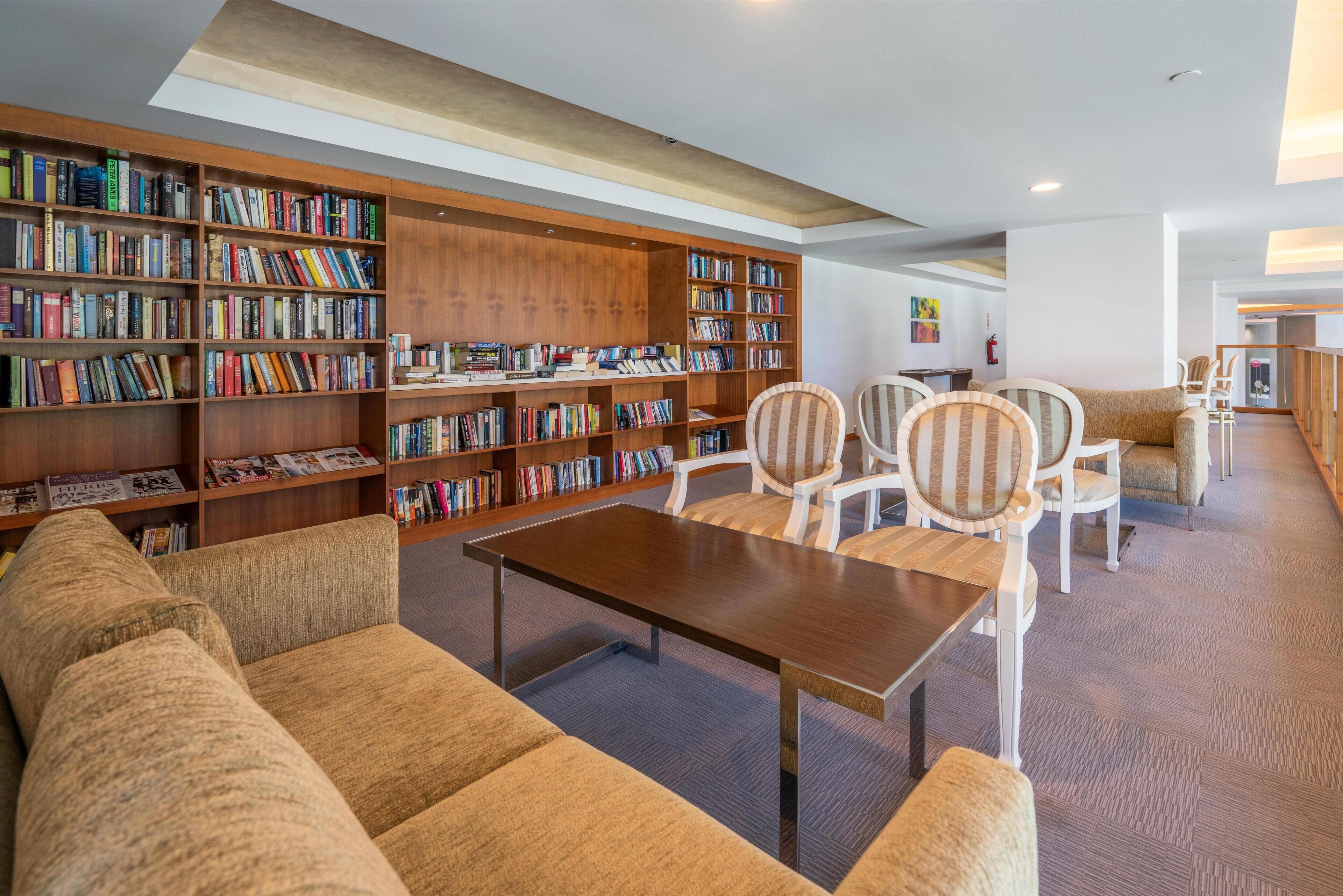 Uma biblioteca com estantes, um sofá e cadeiras.