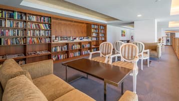 Uma biblioteca com estantes, um sofá e cadeiras.
