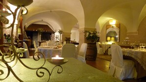 An indoor dining area with tables set for a meal, featuring arched ceilings and a candle centerpiece. - Relais del Castello di Oviglio (Oviglio)