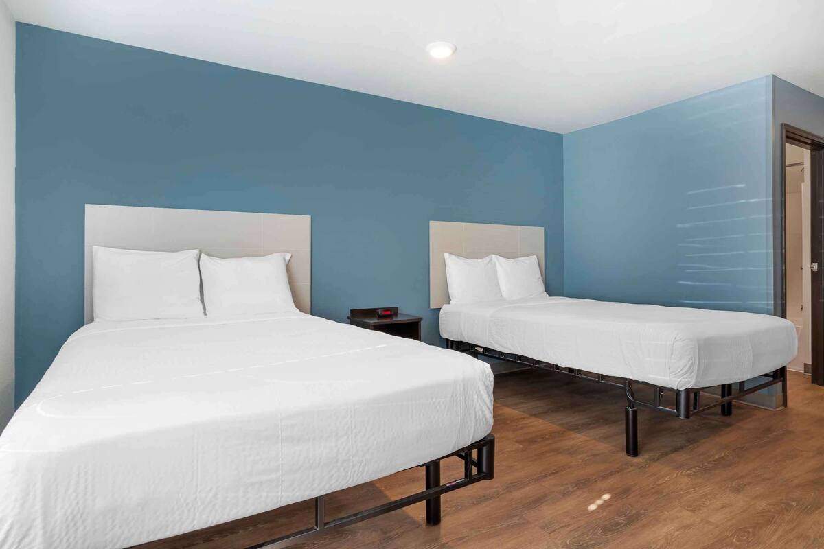 Ett hotellrum med två separata sängar, trägolv och blå väggar.