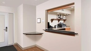 A hotel room with a wooden floor, a black desk, a mirror, and a small kitchenette area with a coffee machine and a microwave. - Extended Stay America Select Suites - Pensacola - Northwest (Pensacola)