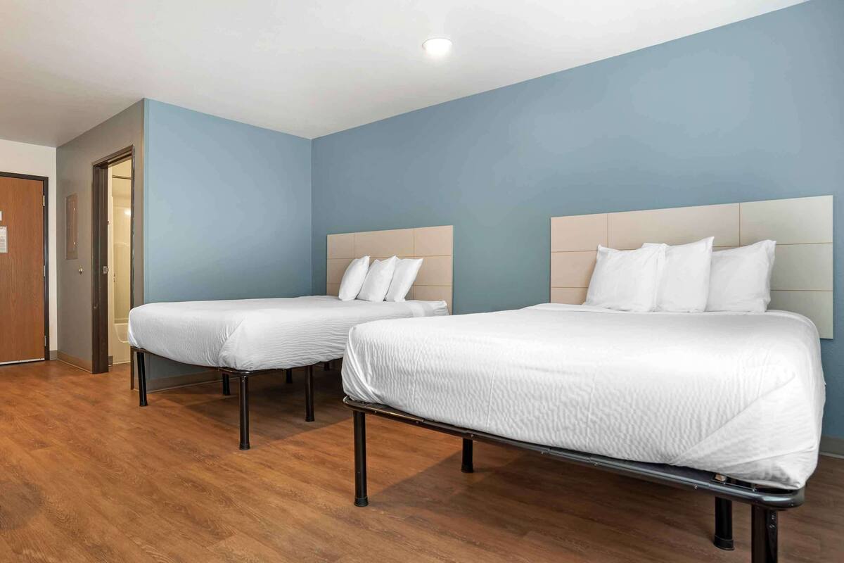 Een hotelkamer met twee bedden, houten vloeren en een blauwe wand.
