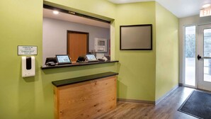 A reception area with a check-in counter, a digital kiosk, and a sign indicating check-in and check-out times. - Extended Stay America Select Suites - Pensacola - Northwest (Pensacola)