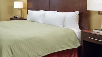 Ein Hotelzimmer mit Bett, Nachttisch mit Lampe und Schreibtisch mit Telefon.