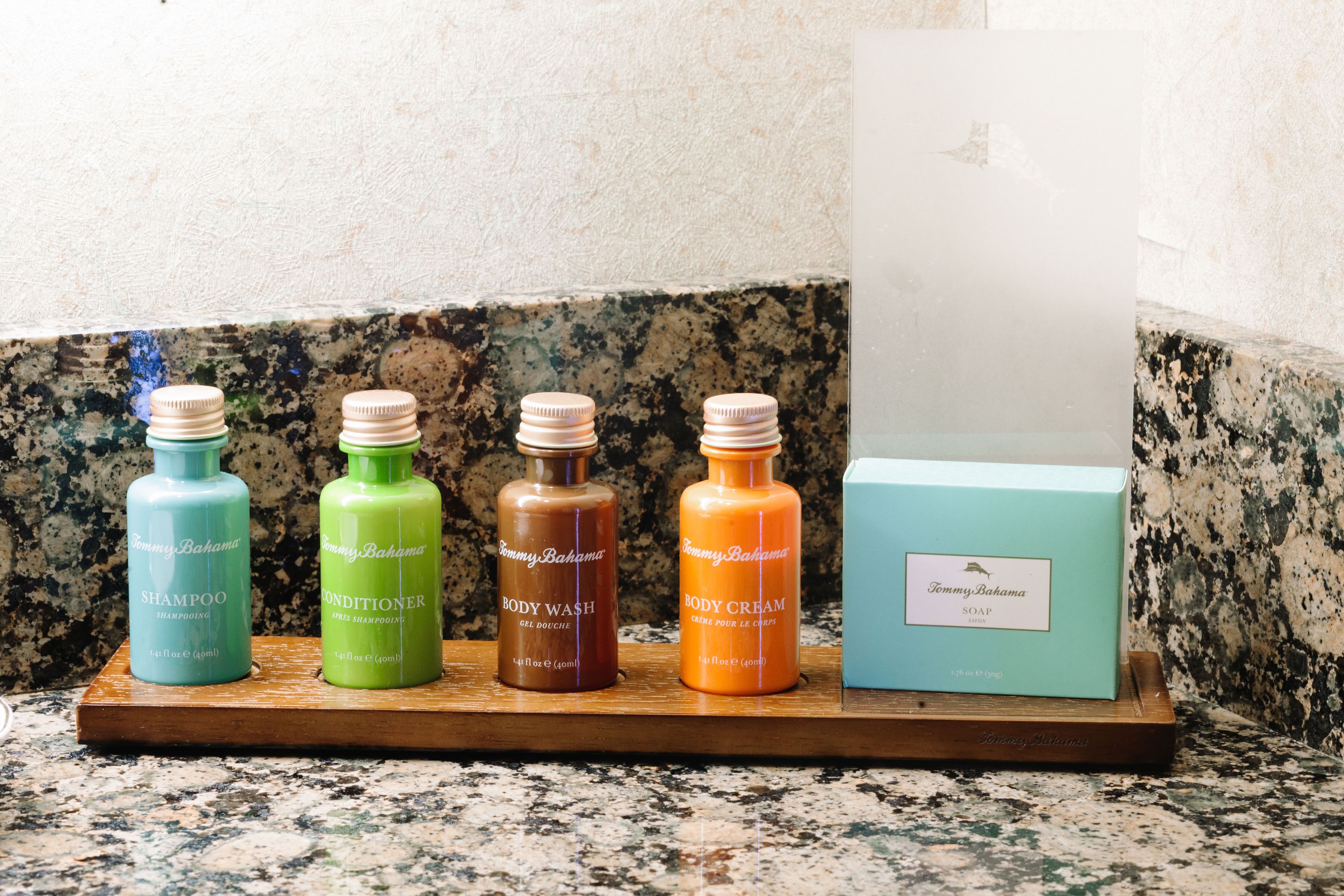 A wooden shelf with four bottles of Tommy Bahama products and a box of soap.