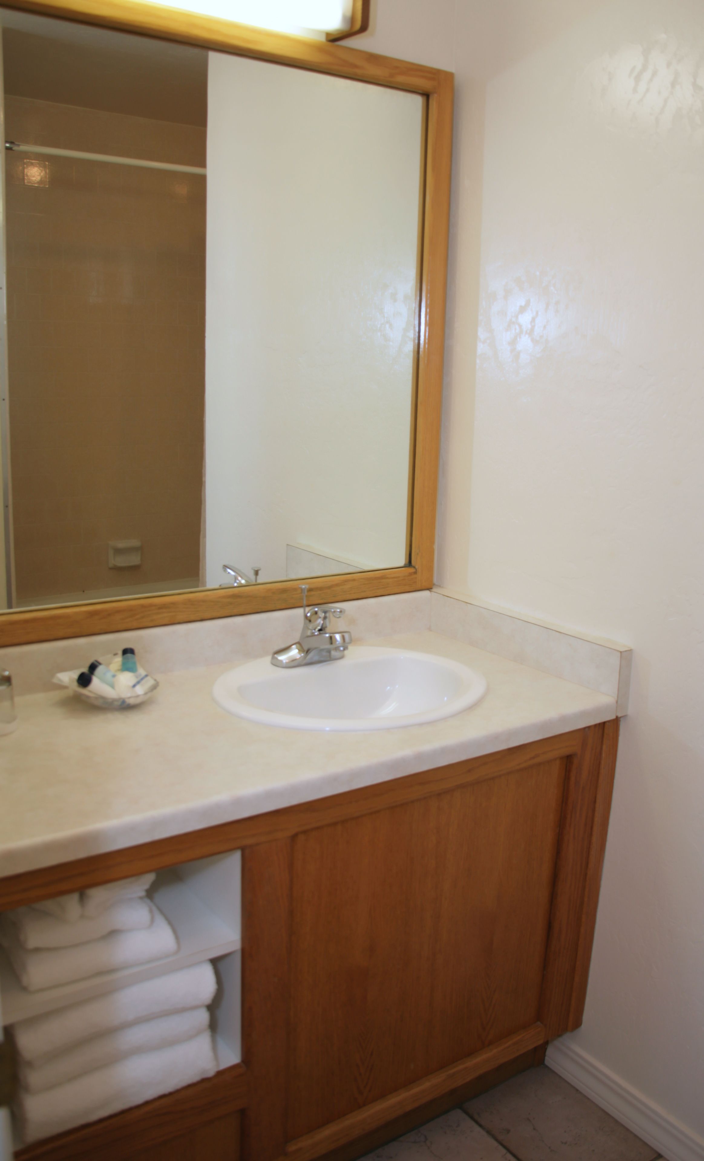 A bathroom with a wooden vanity, a white sink, and a mirror.