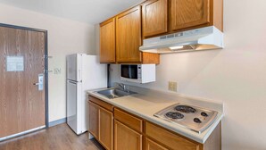 A kitchen with wooden cabinets, a microwave, a refrigerator, and a stove. - Extended Stay America Select Suites - Firestone (Longmont)