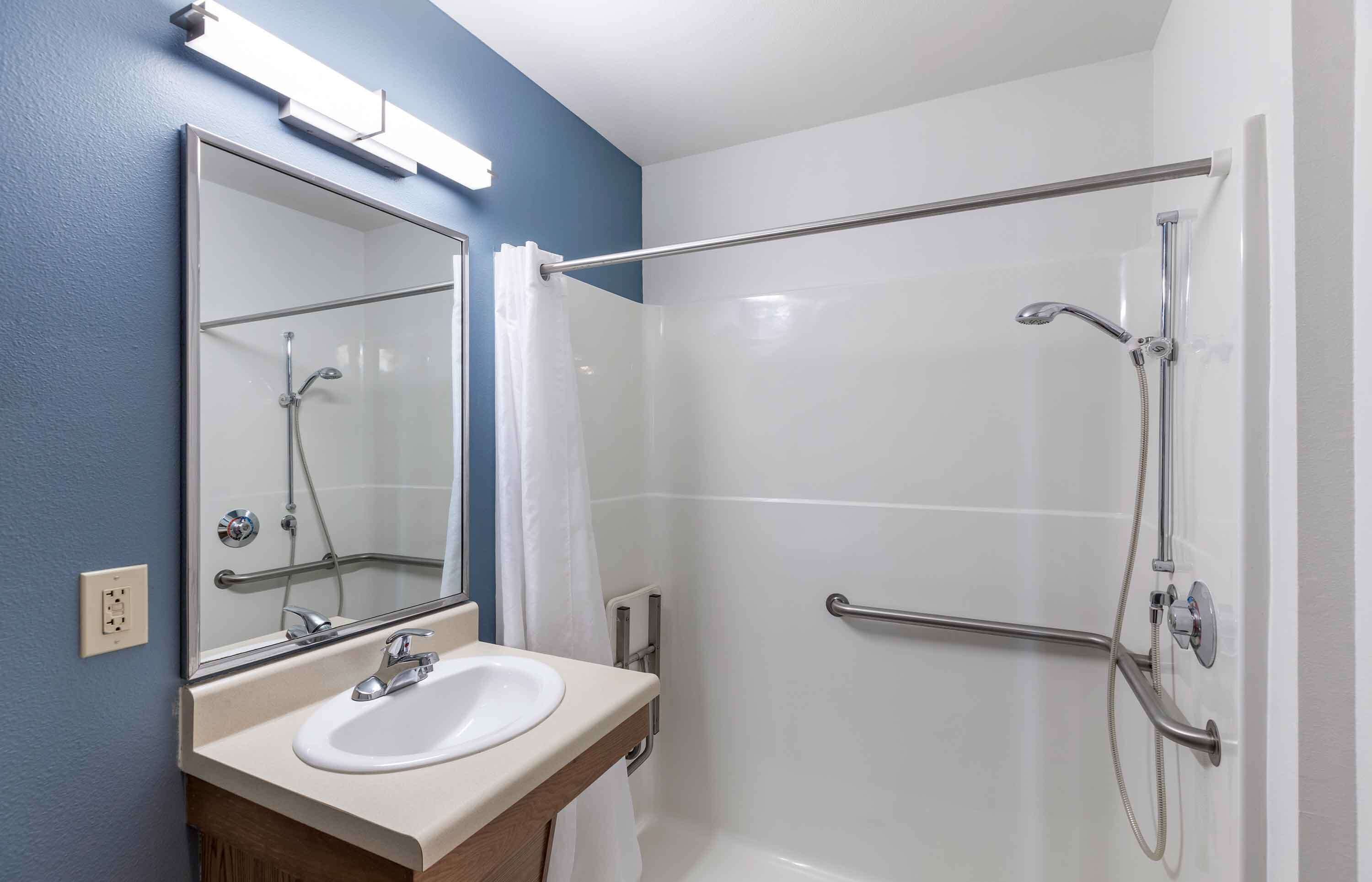 Un baño con cabina de ducha de vidrio, un lavamanos blanco y un espejo.