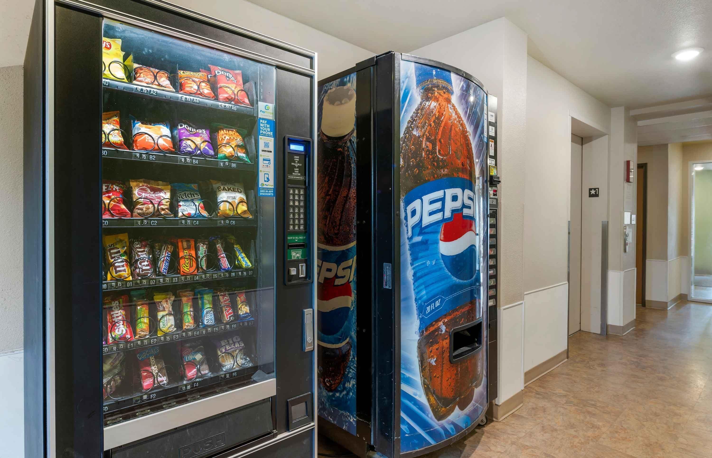 Máquina expendedora con aperitivos y un dispensador de Pepsi en un pasillo.