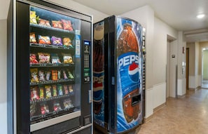 Máquina expendedora con aperitivos y un dispensador de Pepsi en un pasillo.