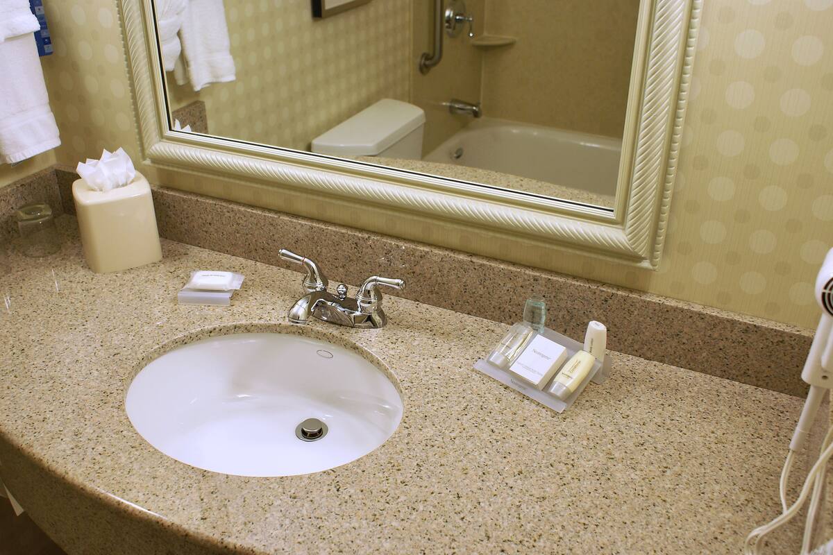 A bathroom with a sink, mirror, and toiletries.