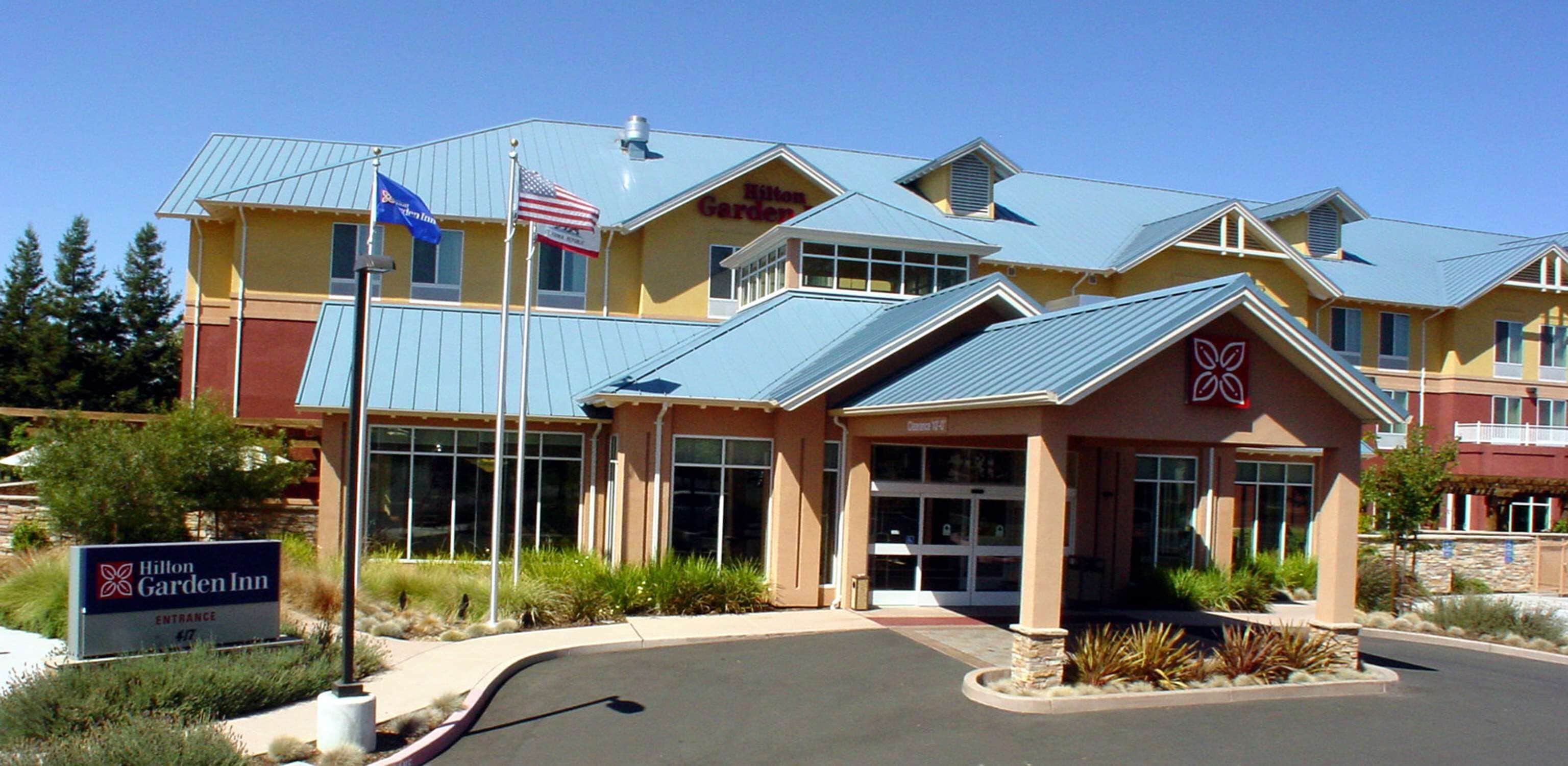 A Hilton Garden Inn with a modern design, featuring a large entrance and a flagpole with the American flag.