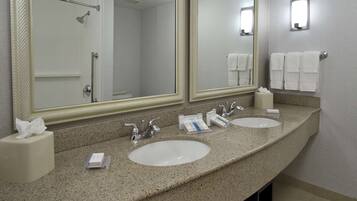 Ein Badezimmer in einem Hotel mit zwei Waschbecken, einem großen Spiegel und einer Dusche.