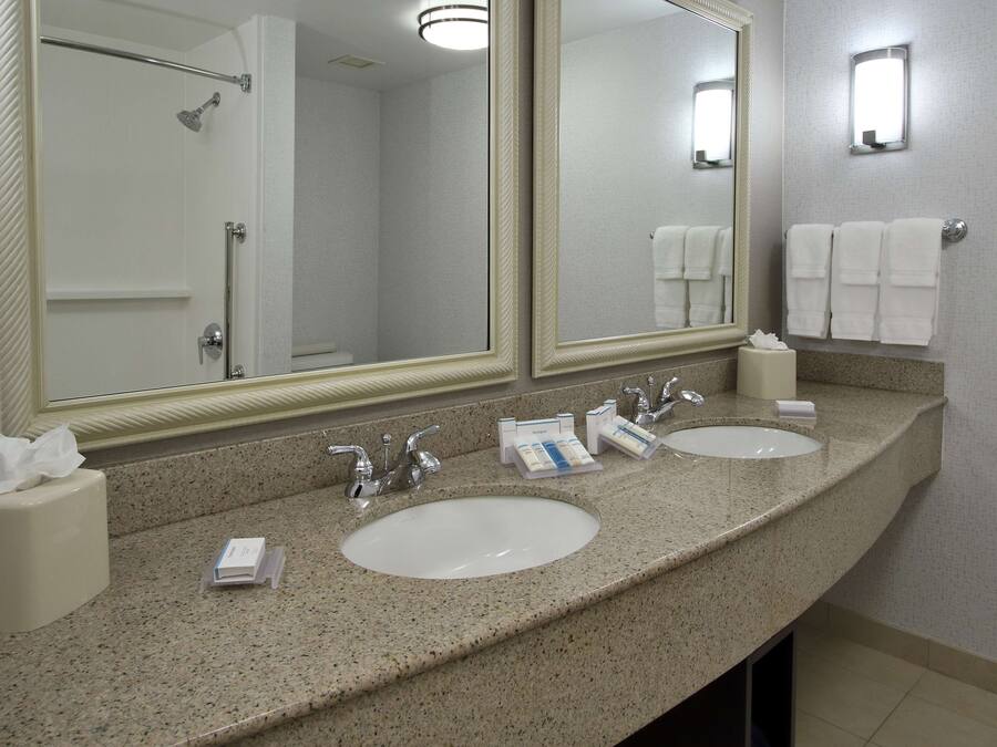 Ein Badezimmer in einem Hotel mit zwei Waschbecken, einem großen Spiegel und einer Dusche.