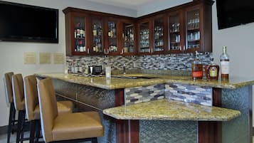 A bar area with granite countertops, bar stools, and a variety of liquor bottles.