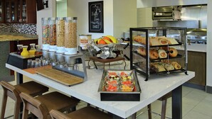 A breakfast bar with various food items and a waffle batter station. - Hilton Garden Inn Sonoma County Airport (Santa Rosa)