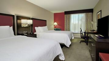 A hotel room with two beds, a desk with a computer, a chair, and a television.