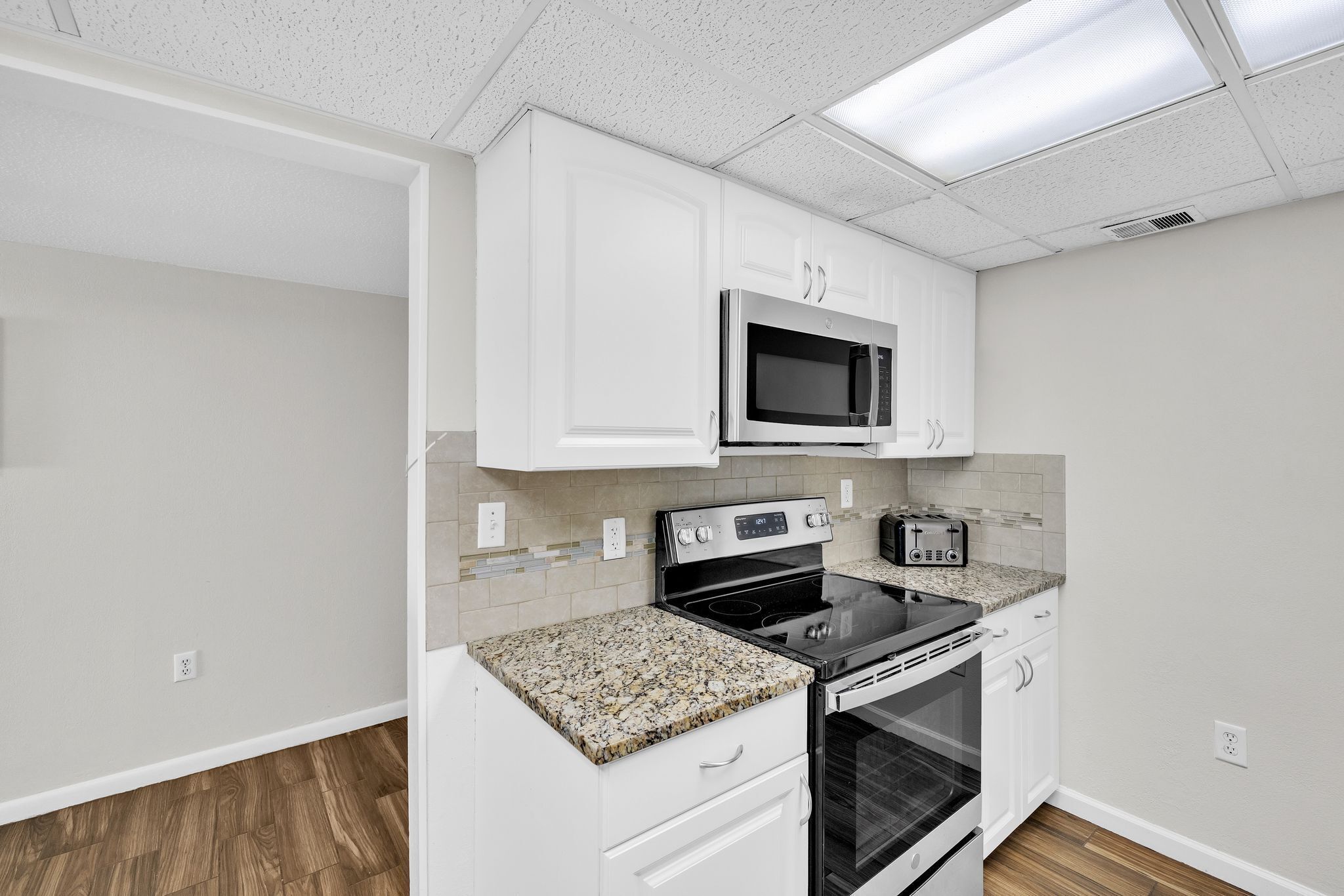 A kitchen with white cabinets, a microwave, a stove, and a toaster.