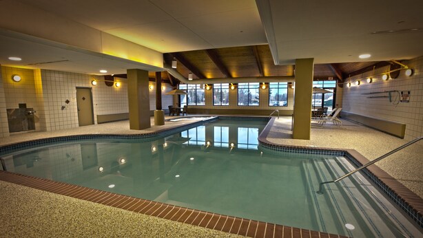 An indoor swimming pool with clear water, tiled walls, and a bench area.
