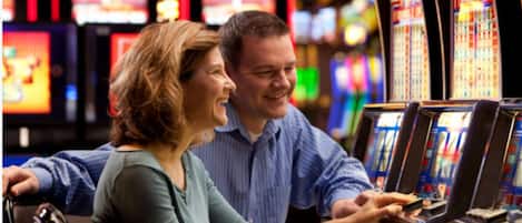 A couple at a slot machine in a casino.