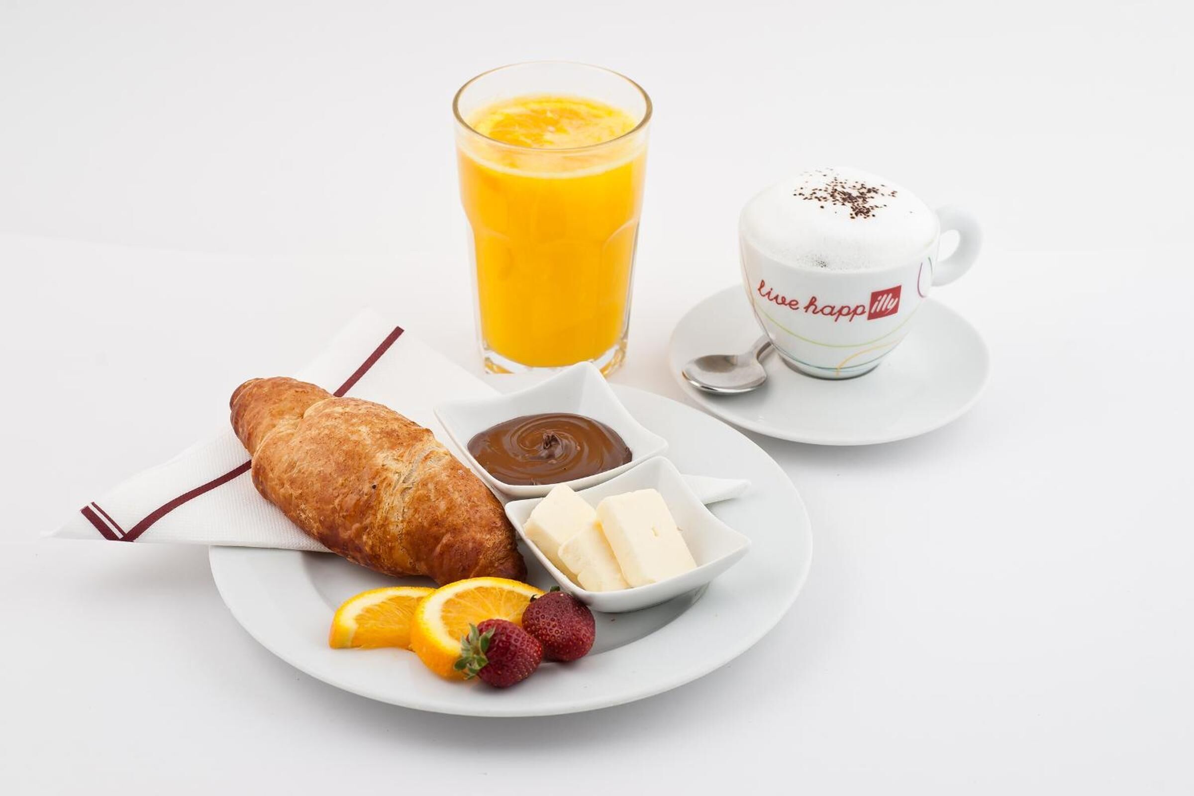 Un plato de desayuno con croissant, jugo de naranja, café y fruta.