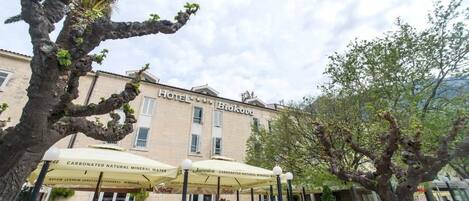 A hotel with outdoor seating and umbrellas labeled "Carbonated Natural Mineral Water".