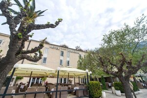 A hotel with outdoor seating and umbrellas labeled "Carbonated Natural Mineral Water".