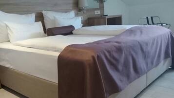 Een moderne hotelkamer met een groot bed, een houten hoofdbord en een klein nachtkastje met lampen.
