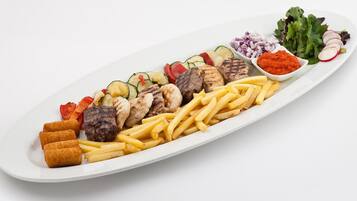 En tallrik med grillat kött, pommes frites och olika sorters grönsaker.