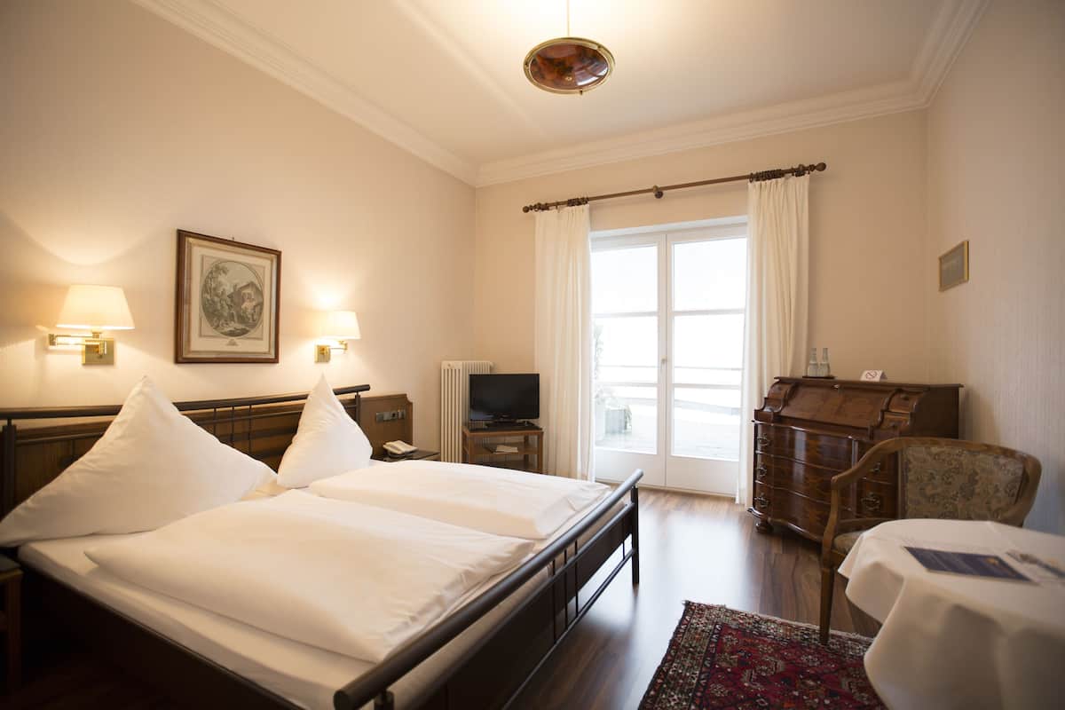 A hotel room with a double bed, bedside lamps, a television, a dresser, and a chair.