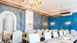 Een vergaderzaal met lange tafels, witte stoelen en een kroonluchter.